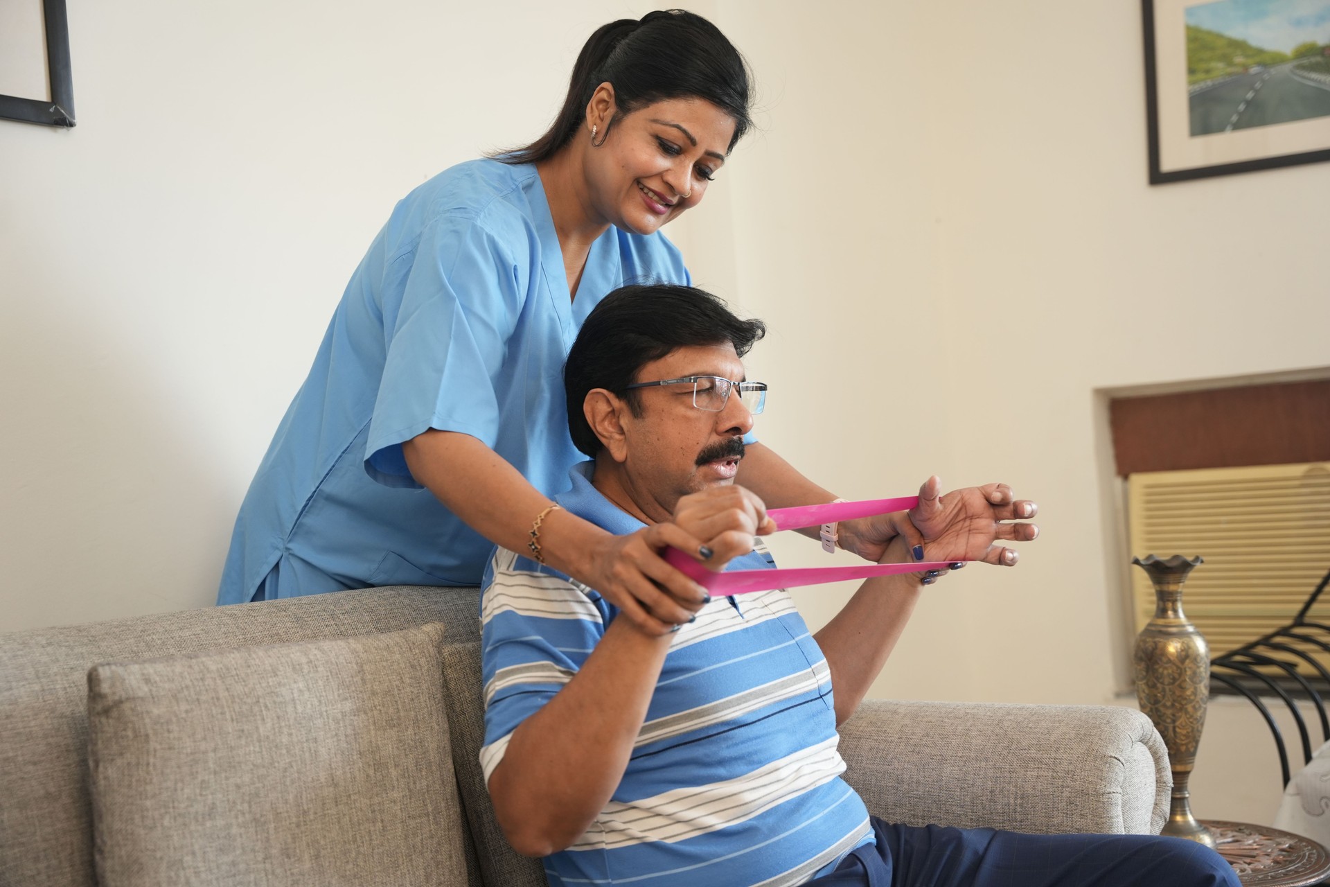 Indian female physiotherapist, stretching band and mature patient, medical care and wellness. Orthopedic,healthcare and chiropractor with person for physical therapy, rehabilitation and exercise
