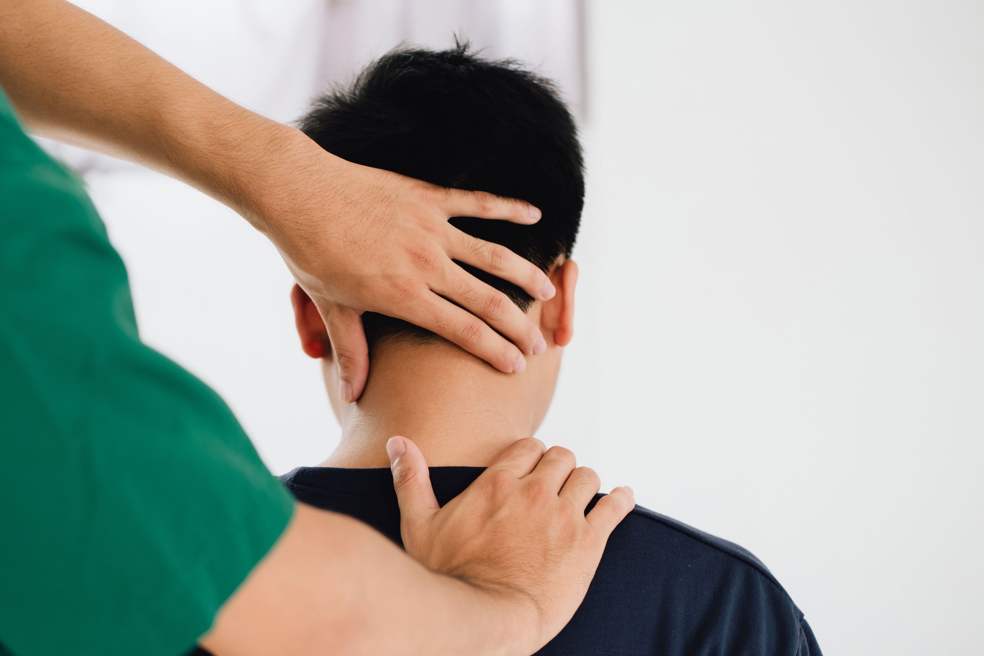 physiotherapist massage therapist holding male client's head and massaging tight neck muscles the result of prolonged use of mobile phones.Office Syndrome