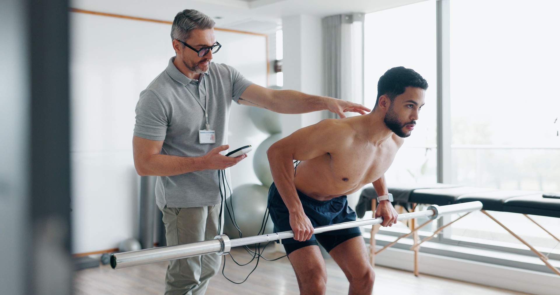 Physiotherapy, fitness and monitor with man in clinic for biofeedback, muscle stimulation and track progress. Rehabilitation, healthcare and training with people for chiropractor, help and healing