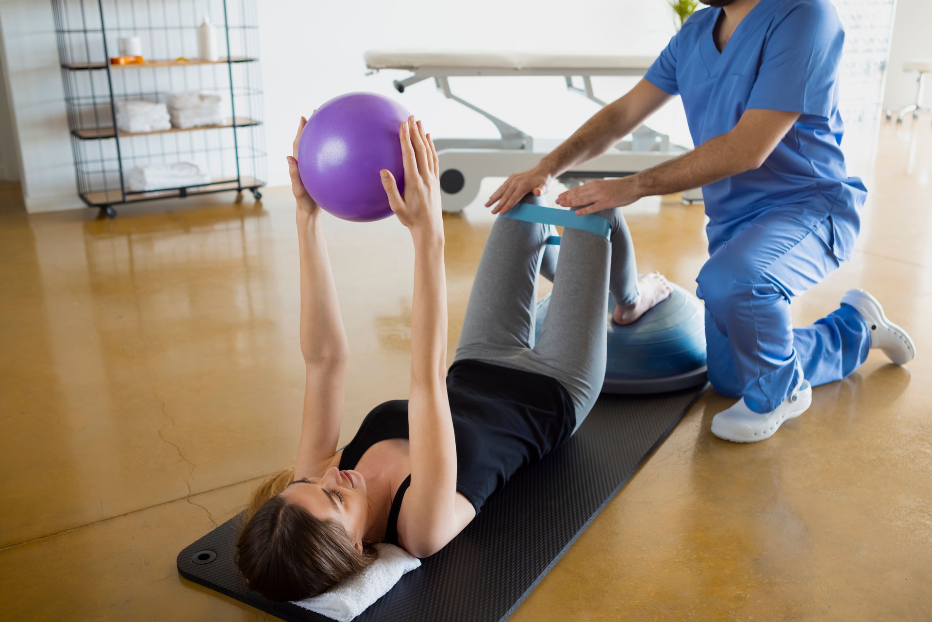 Female patient lying down on a mat exercising with her physiotherapist.
