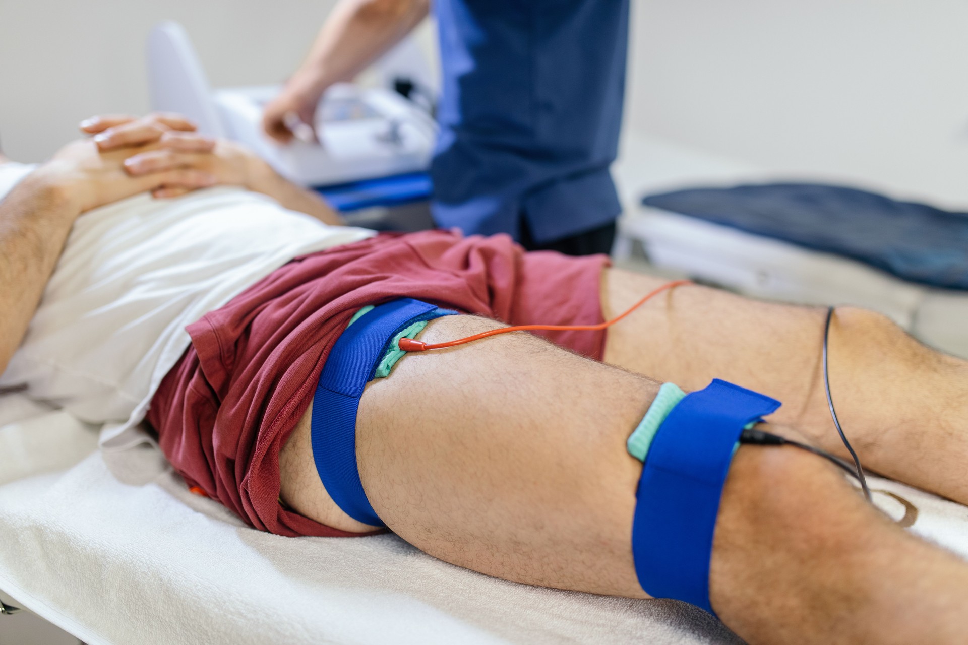 Physiotherapist applying electro stimulation to legs in physical therapy