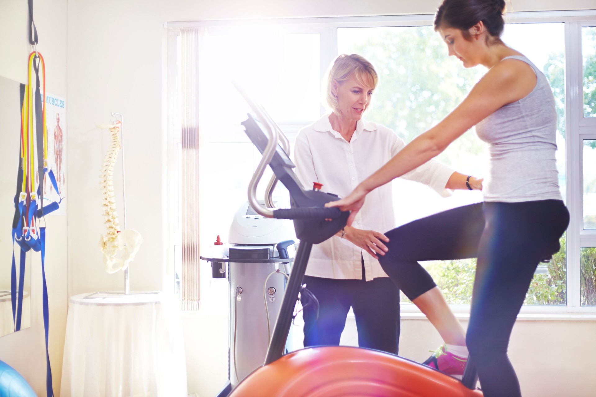 Physical therapist guiding woman on stationary bike