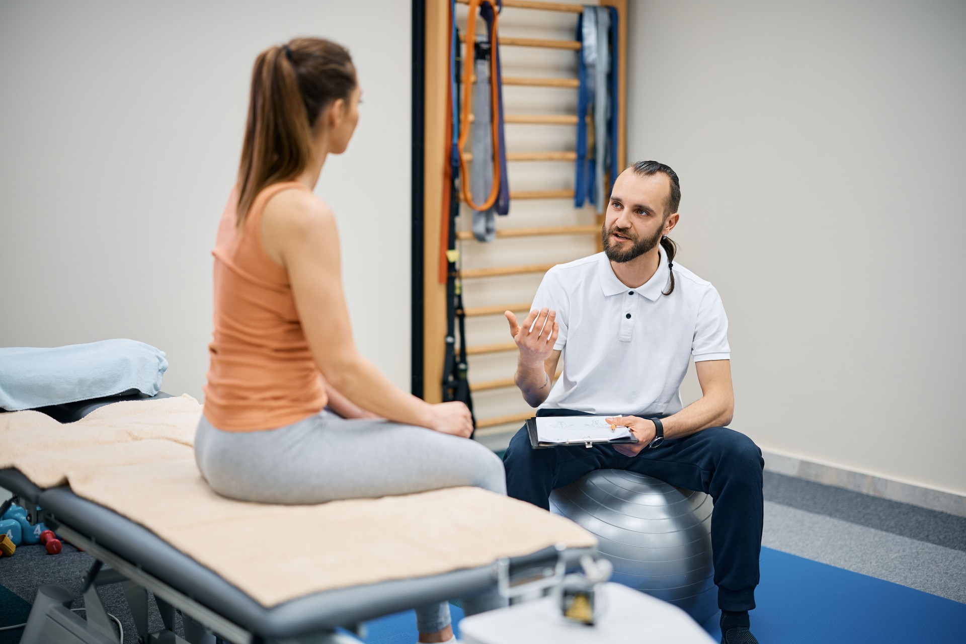 Professional physiotherapist talking to female patient at physical therapy center.